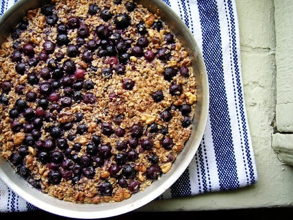 Blueberry baked oatmeal in a round metal pan set on a striped kitchen towel