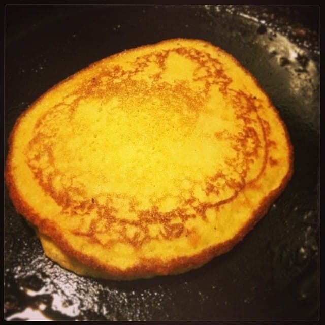A golden pancake cooking in a nonstick skillet