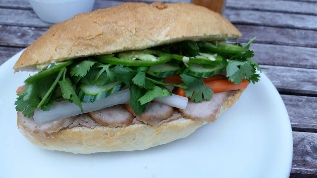 Bánh mì in a crusty roll filled with sliced pork, pickled daikon and carrot, cucumber, jalapeño and cilantro