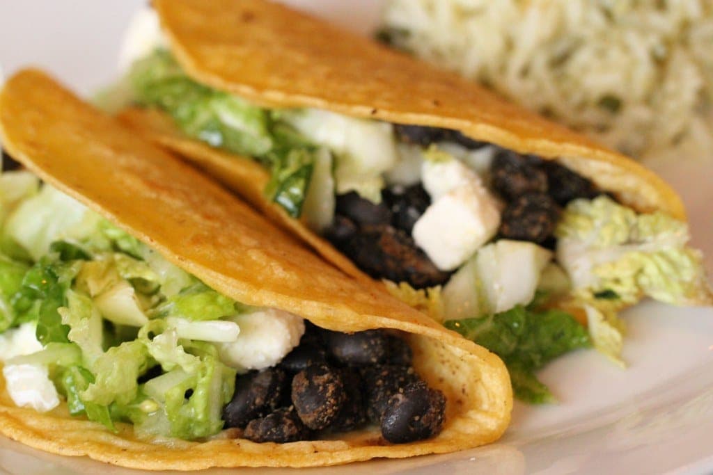 Crispy corn tacos filled with black beans, shredded cabbage and crumbled white cheese