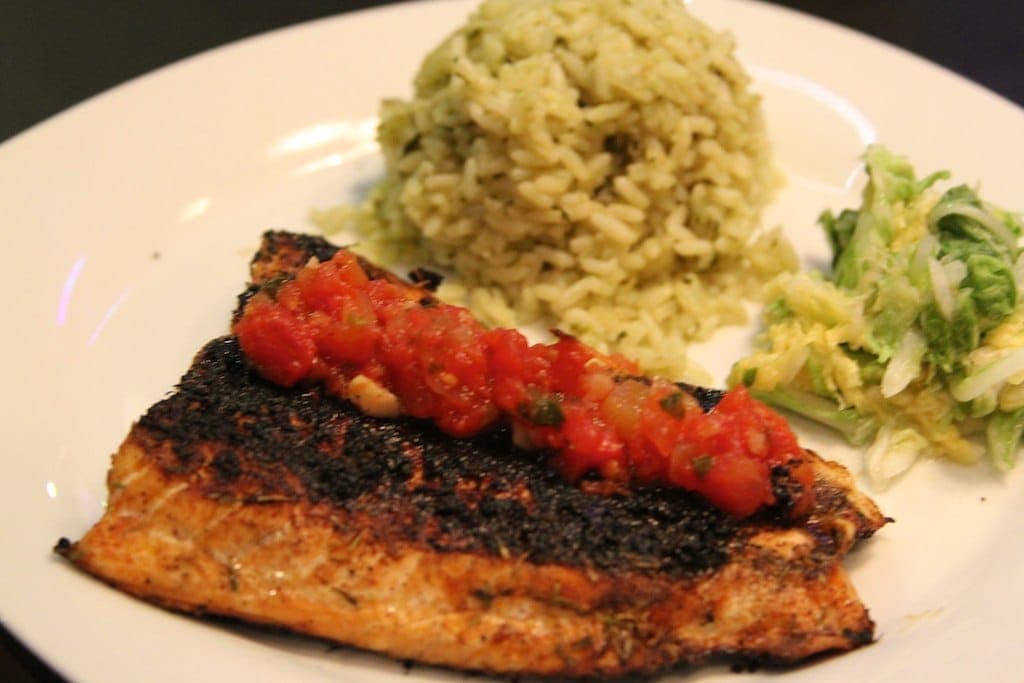 Blackened salmon fillet topped with tomato salsa, served with herbed rice and slaw