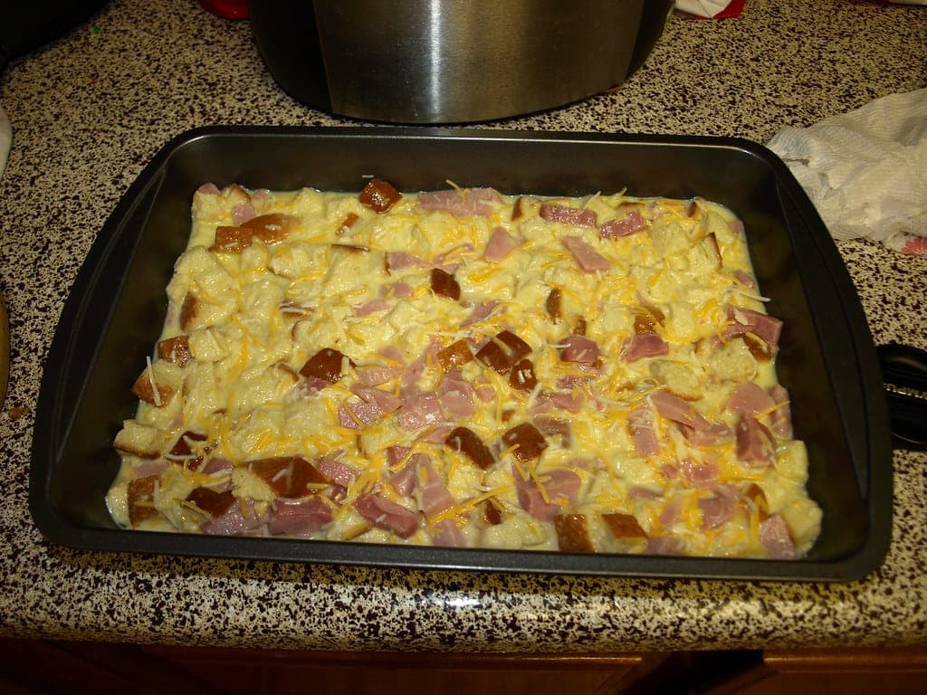 A baked egg, ham and cheese breakfast casserole in a rectangular metal pan