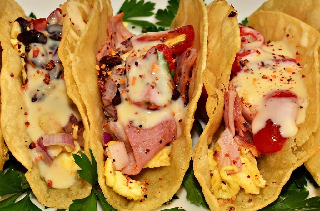 Flour tortilla breakfast tacos filled with scrambled egg, ham and cheese