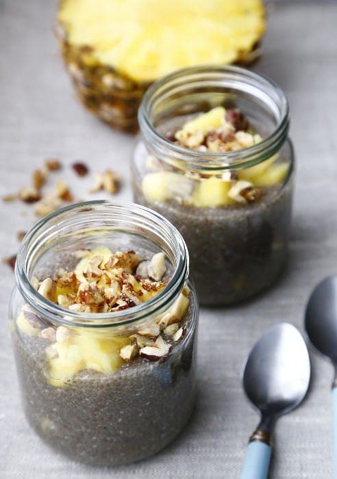 Glass jars of chia pudding layered with fruit and nuts