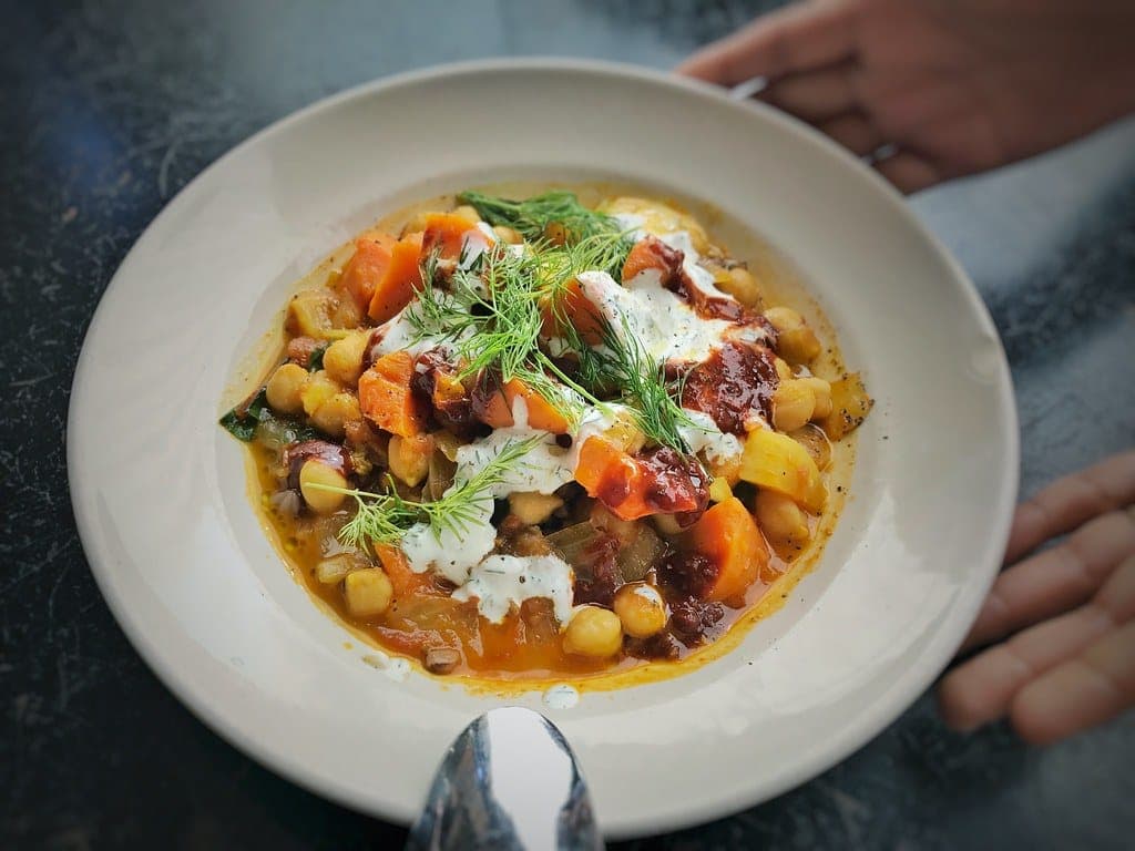 Plate of chickpea and vegetable stew with squash and tomato, finished with yogurt and fresh dill