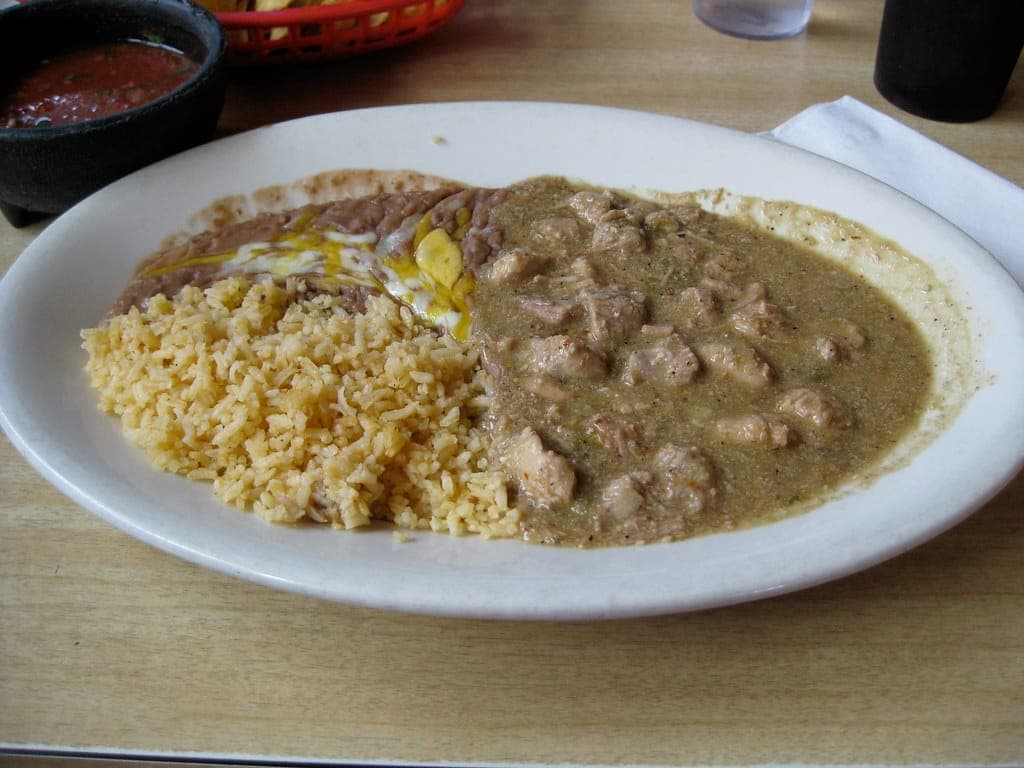 Plate of pork chile verde in green sauce with Mexican rice and refried beans