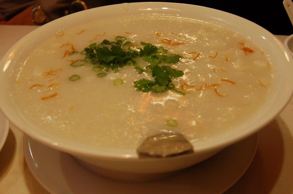 A bowl of smooth rice congee topped with chopped scallions