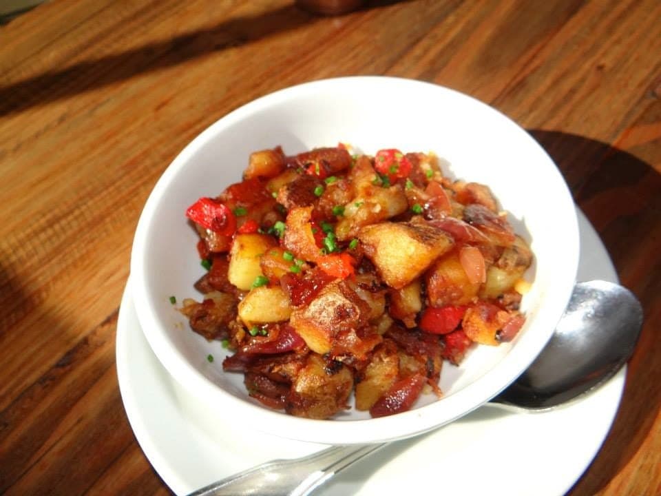 A bowl of diced skillet potatoes with red peppers and onions