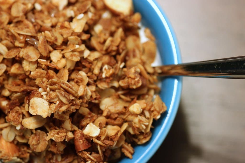 Golden clusters of homemade granola in a blue bowl with a spoon