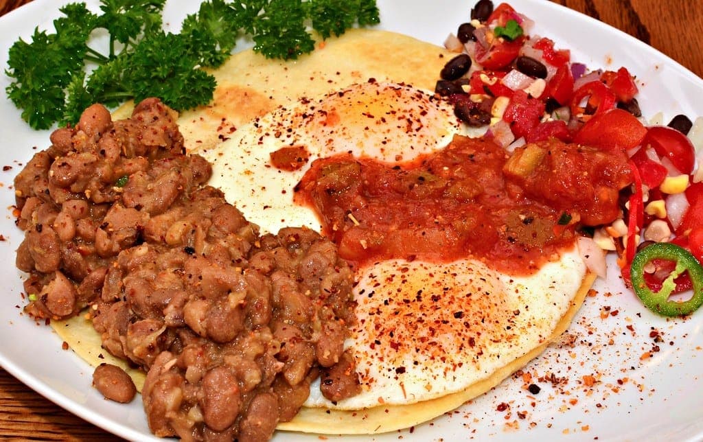 Fried eggs on tortillas with refried beans and red ranchero sauce