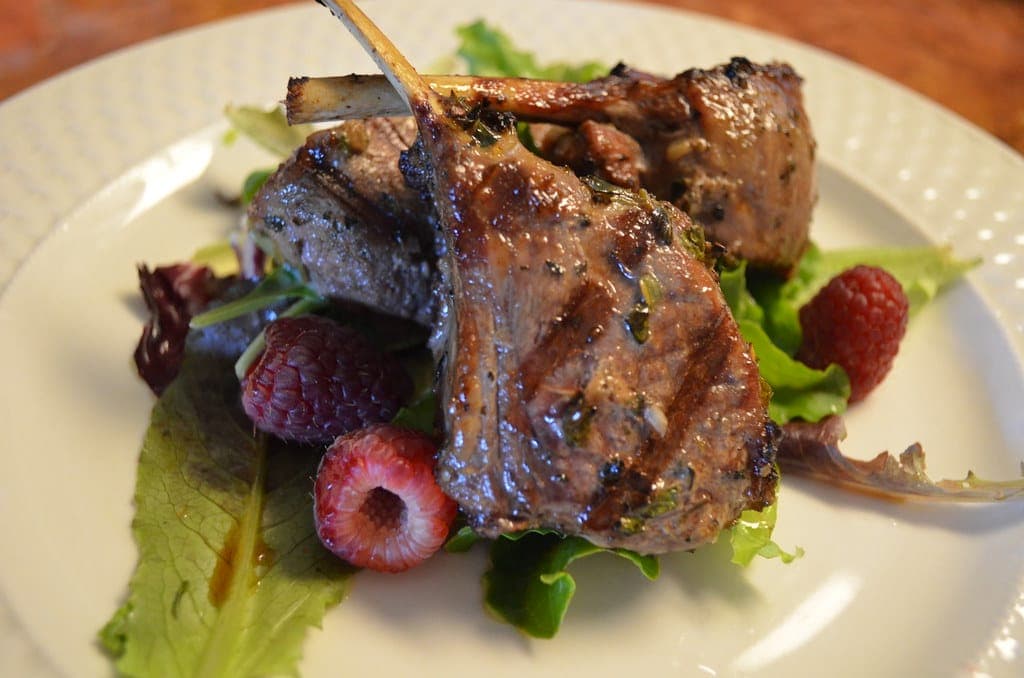 Grilled lamb chops with herbs on mixed greens with fresh raspberries