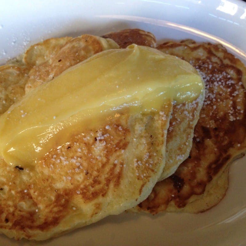 A stack of pancakes topped with glossy lemon curd