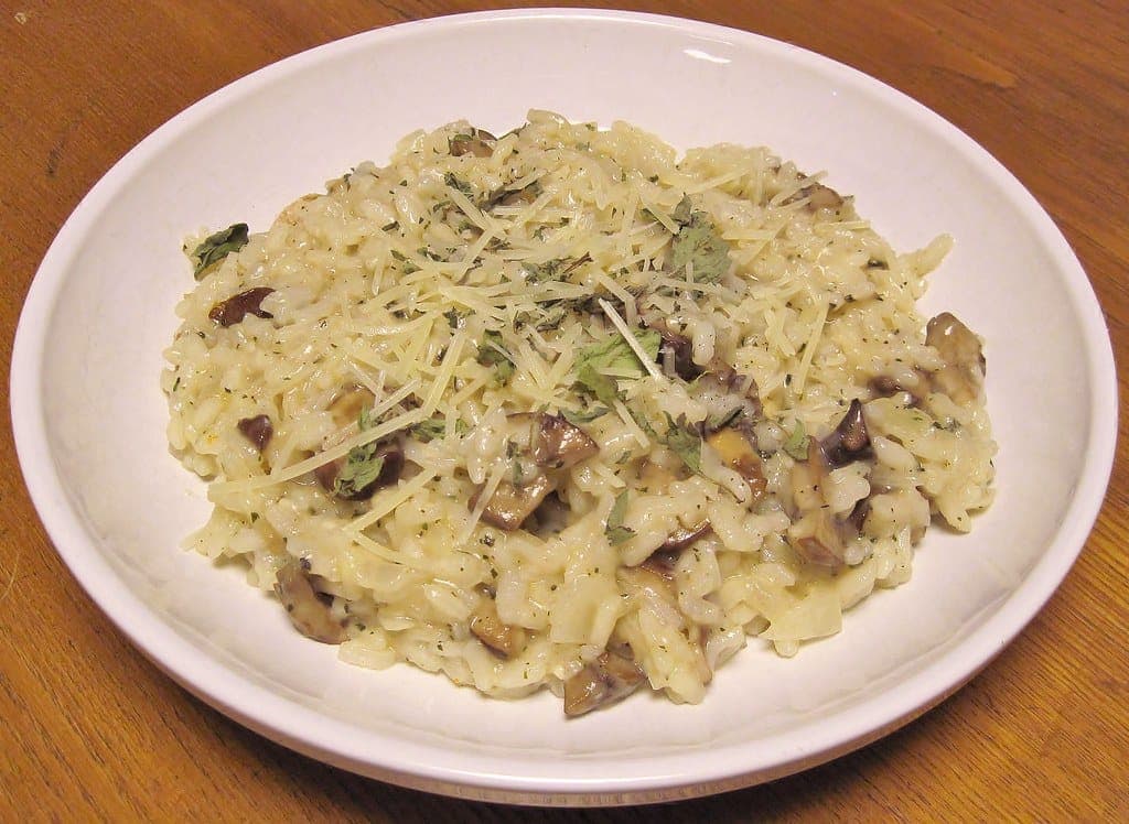 Plate of creamy mushroom risotto topped with grated Parmesan and herbs