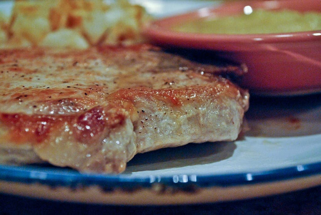 Close-up of a golden pan-seared pork chop on a blue-rimmed plate
