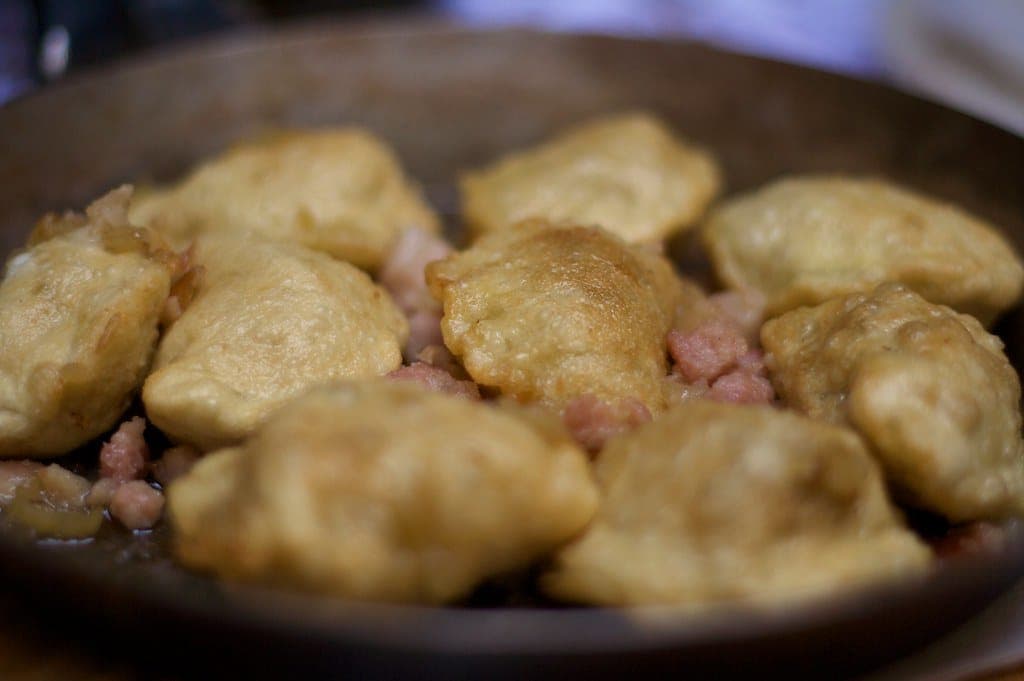 Pan-fried pierogi with crisp golden edges and bits of crisp topping in a skillet