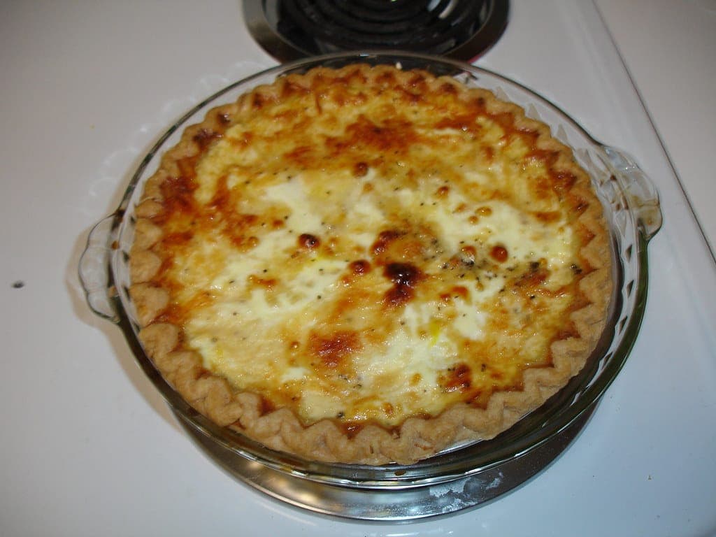 A whole golden quiche baked in a glass pie dish