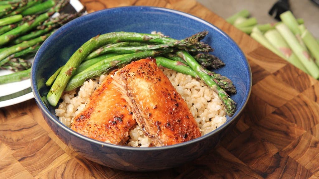 Roasted salmon fillet and asparagus over brown rice in a blue bowl