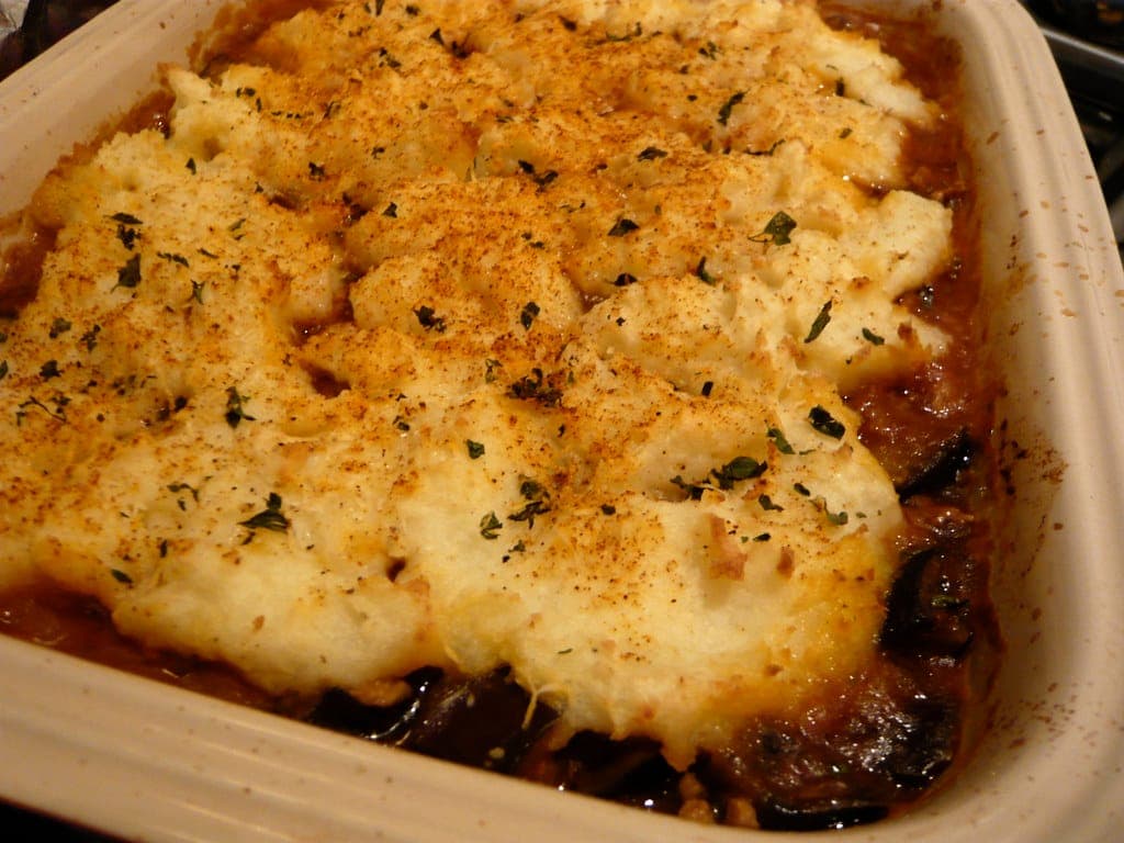 Baked shepherd's pie with a golden, herb-flecked mashed potato topping in a ceramic dish