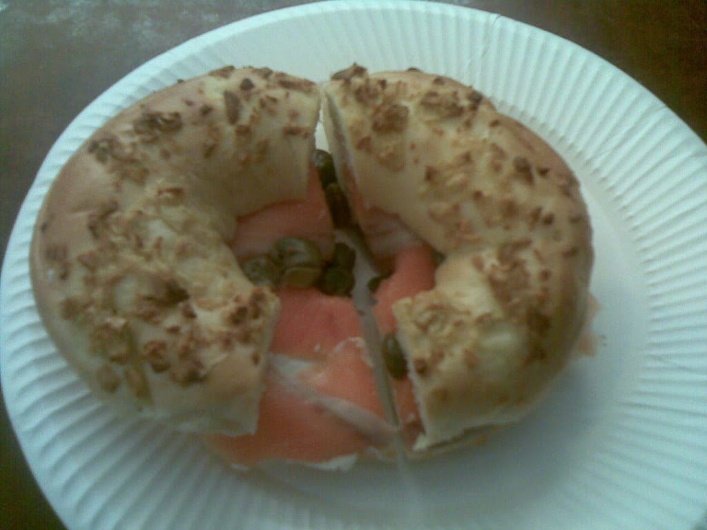 Seeded bagel cut in half and filled with cream cheese, smoked salmon and capers