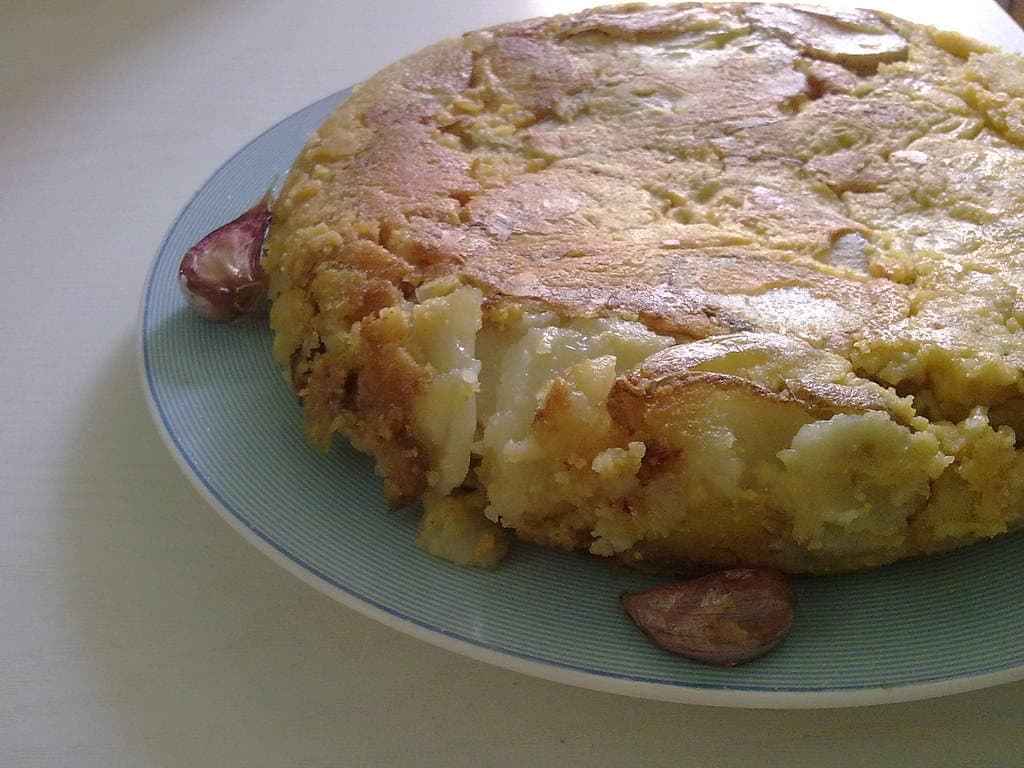 A thick, golden Spanish potato tortilla on a plate