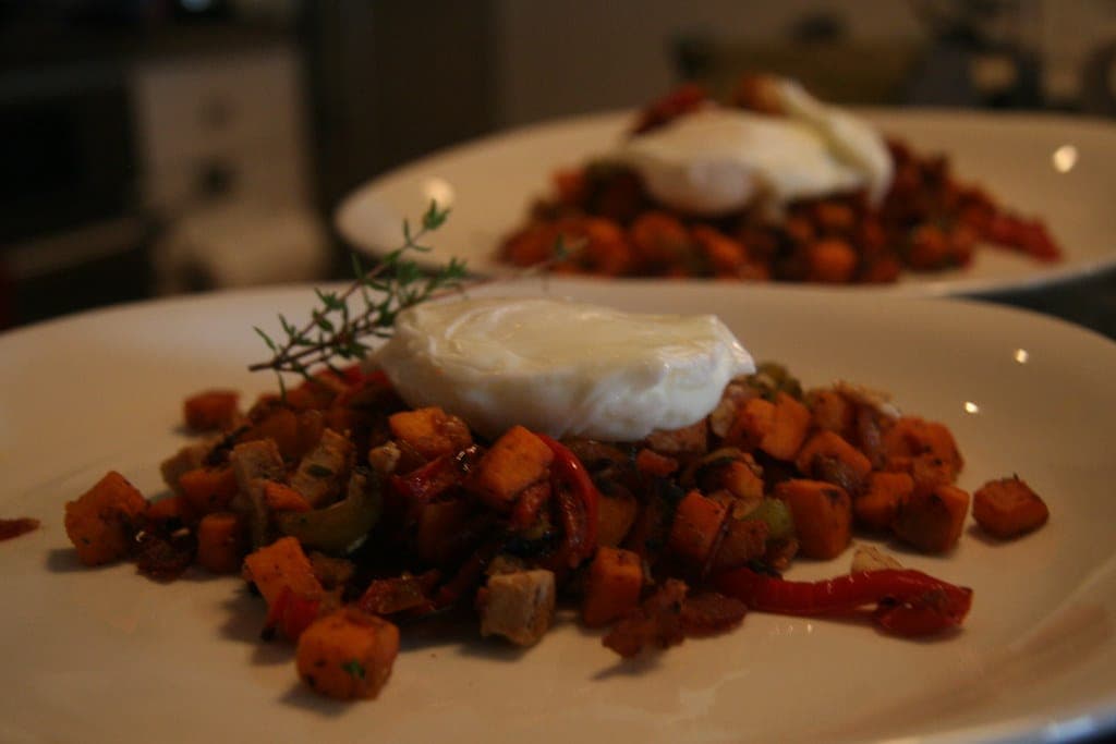 Sweet potato hash with peppers and onions topped with a poached egg