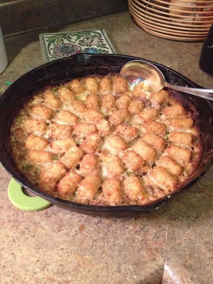 Cast-iron skillet of tater tot casserole with neat rows of golden tots