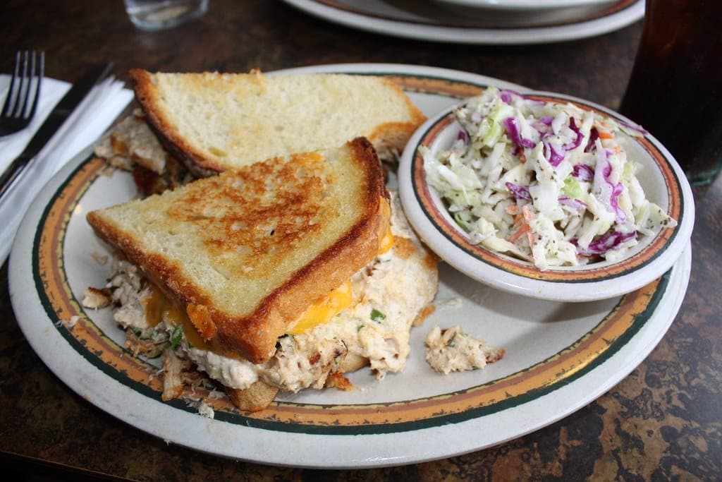 Tuna melt on toasted bread with melted cheese, served with a side of coleslaw
