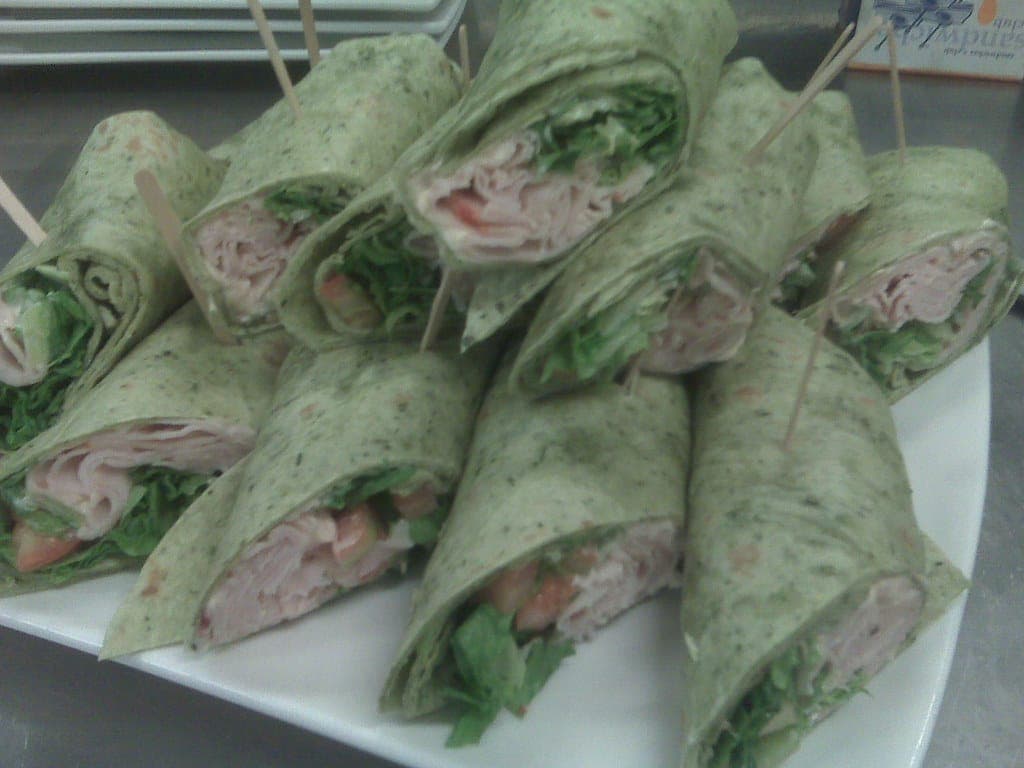 Platter of sliced spinach tortilla wraps filled with turkey and greens