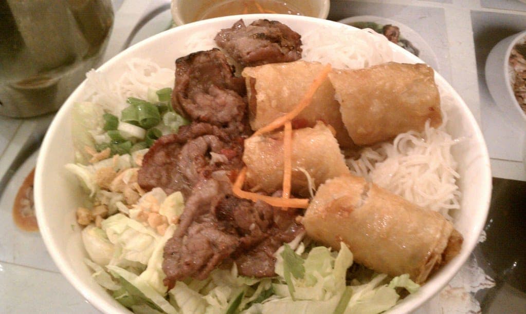 Vermicelli noodle bowl with grilled meat, crispy spring rolls, lettuce and herbs