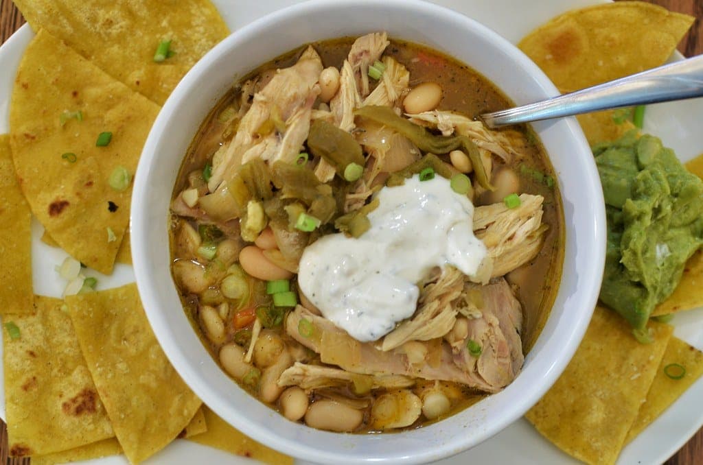 Bowl of white chicken chili with shredded chicken, white beans and sour cream, with tortilla chips